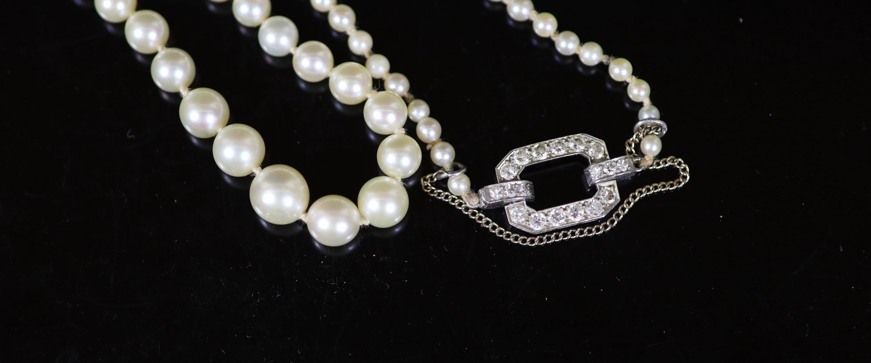 A mid 20th century single strand graduated pearl necklace, with platinum and diamond set open work clasp, signed Cartier with indistinct numbers